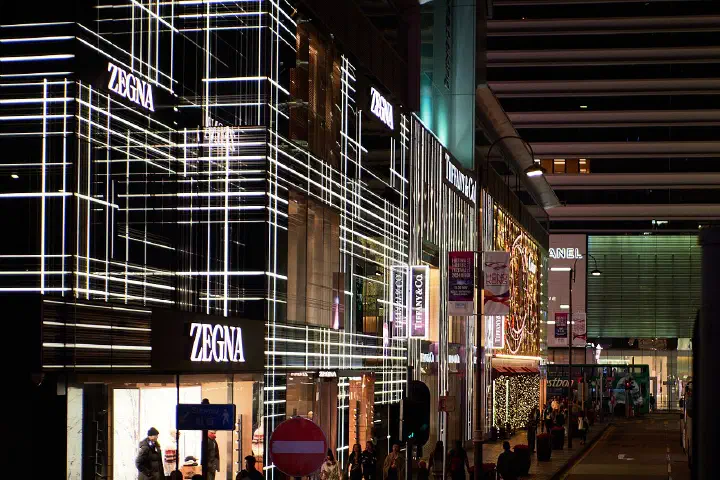 Luxury retail storefronts including Zegna and Tiffany &amp; Co. on a shopping street in Hong Kong at night
