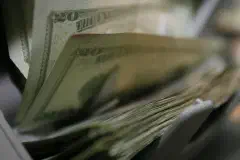 Twenty-dollar bills are counted and packaged for future missions at the Camp Taqaddum disbursing office, June 29, 2006.