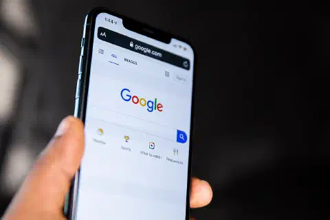 Person holding a phone showing Google homepage