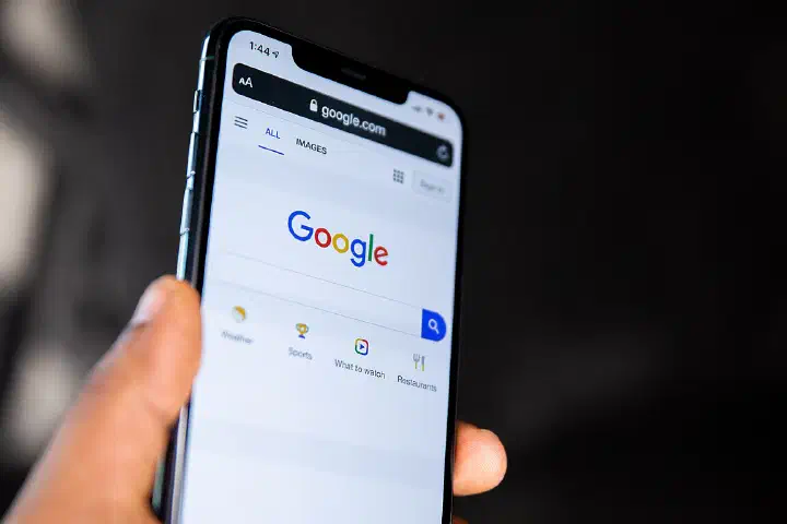 Person holding a phone showing Google homepage